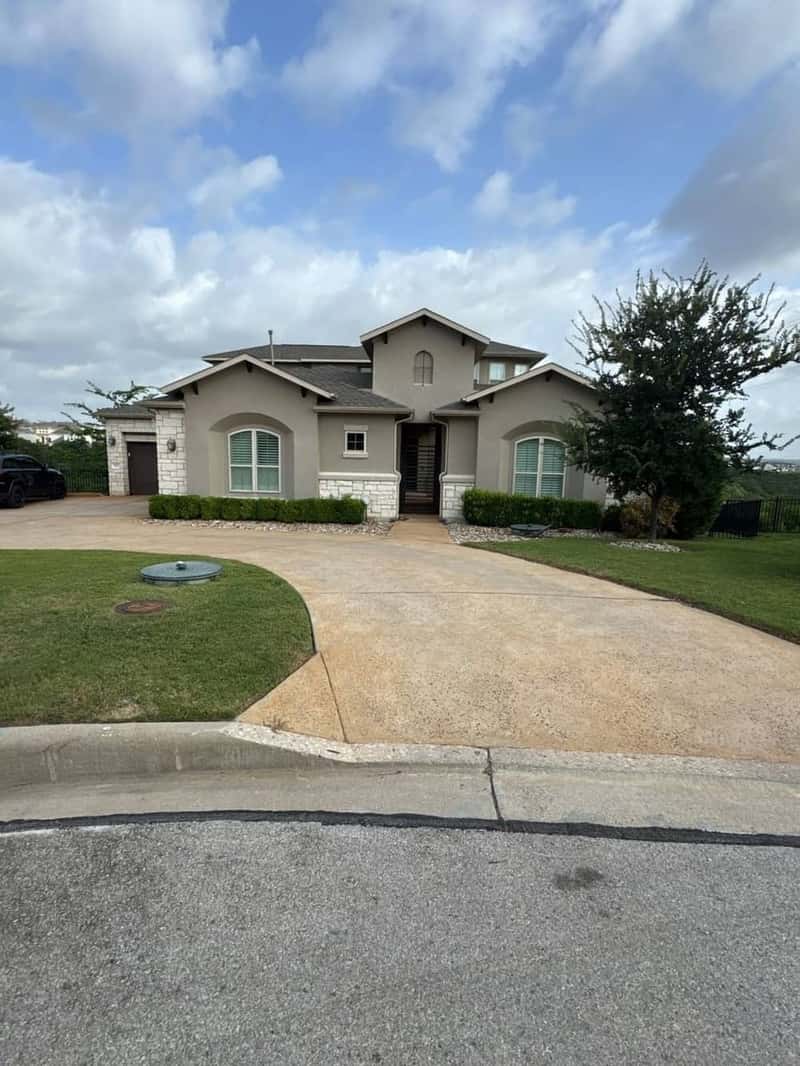 Large two-story stone and stucco home with a circular driveway under a cloudy sky