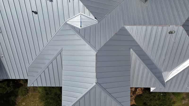Wide shot of a standing-seam metal roof installation showing clean panel seams and hips