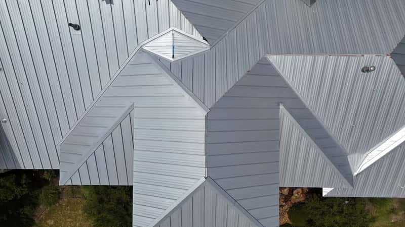 Wide shot of a standing-seam metal roof installation with a distant, unidentifiable crew member