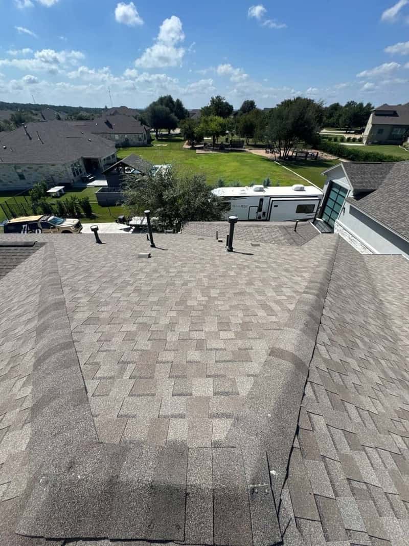 Wide aerial-style view of a clean shingle roof overlooking a quiet neighborhood street
