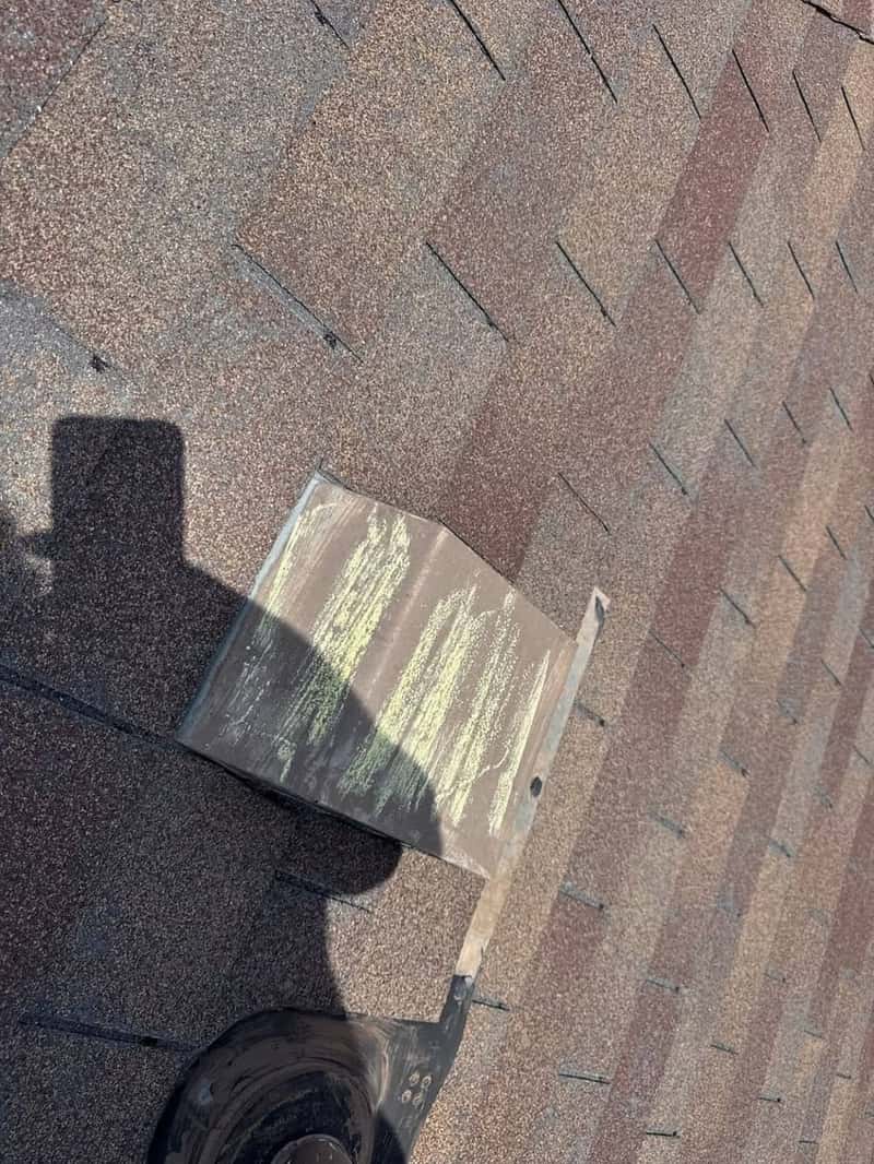 Roof vent boot closeup with chalk hail markings and a worker's shadow nearby