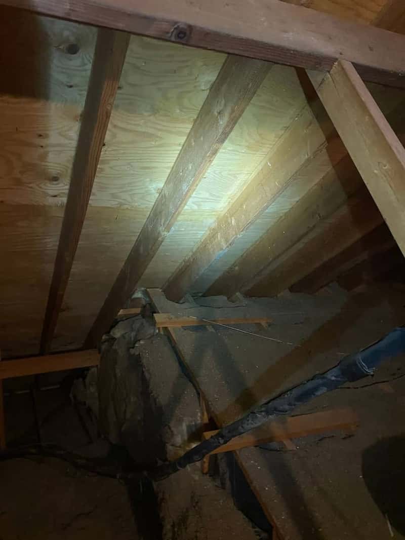 Attic insulation with a black rubber pipe boot sealed around a vent penetration