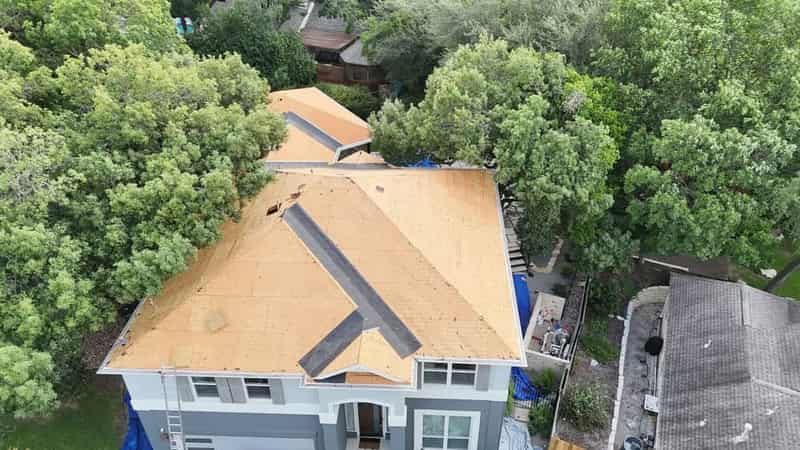 A roof mid tear-off with the decking exposed and the old covering stripped back