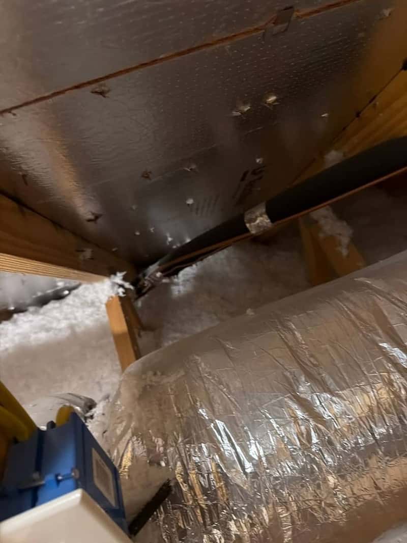 Attic ductwork and reflective insulation viewed beneath the roof deck