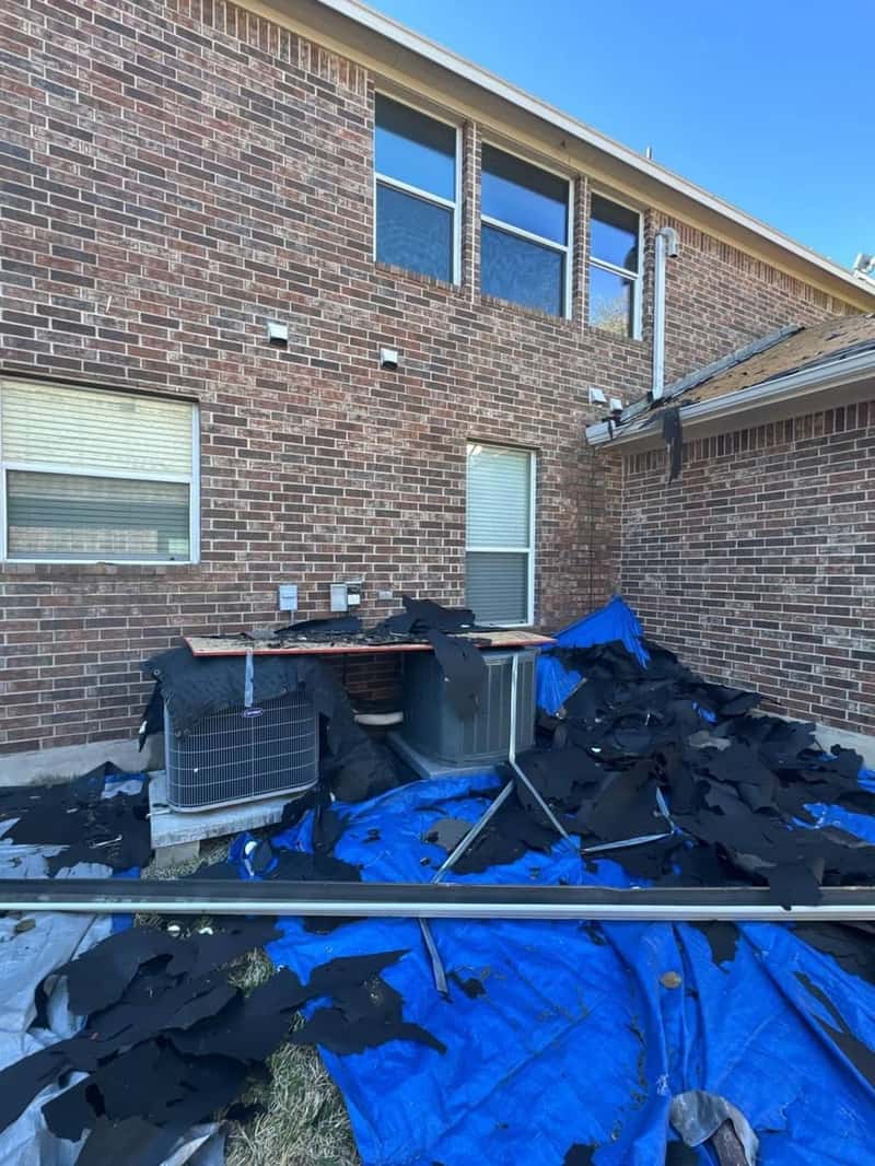 Two AC condenser units tarped against falling shingle debris during a tear-off