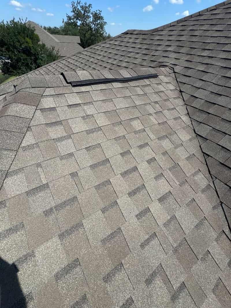 Clean wide shot of a well-maintained shingle roof plane against a clear sky